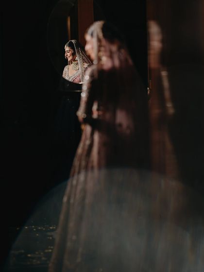 An artistic reflection shot of Vasudha. This creative composition adds depth and a sense of mystery, showing the bride in a moment of quiet reflection before the ceremony.