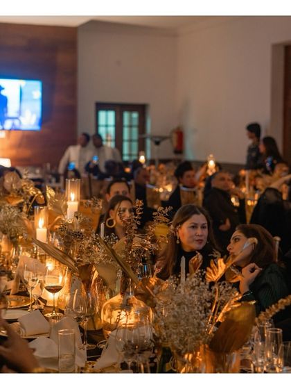 The warm, candlelit ambiance of an elegant evening gathering. Guests engage in conversation over dinner, highlighting the relaxed yet sophisticated environment we strive to create with our bespoke catering services.