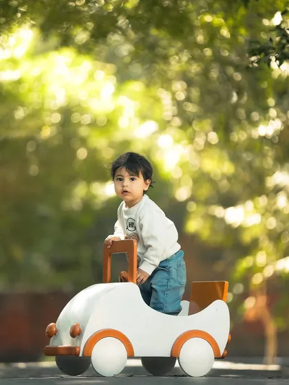 My photography isn't limited to the studio. This outdoor portrait captures a toddler's adventurous spirit, using natural light and a simple prop car to create a dynamic and heartwarming image full of life.