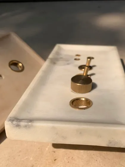 A close-up of the marble switch plate mockup, showing the precise integration of the brass toggles and sockets. This attention to detail ensures a cohesive and high-quality finish in the final home.