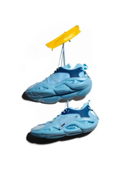 A creative "hanging" shot of light blue sneakers. The use of a yellow prop adds a pop of color and the composition gives the shoes a sense of weightlessness and motion.