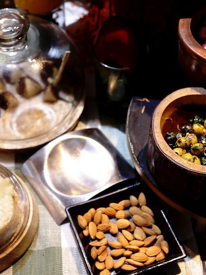 A close-up of a snack station with almonds, olives, and other small bites, presented in beautiful wooden and glass containers.
