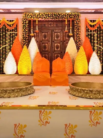 A traditional Haldi or Mehendi stage setup. I used a backdrop of marigold garlands, a rustic carved wooden door, and large urlis for a classic and auspicious feel.