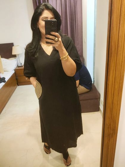 A mirror selfie showing the full length of the black dress. The subtle pocket detail adds a unique touch to this otherwise classic V-neck dress.