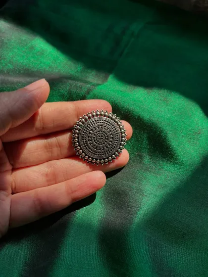 A bold, oxidized silver statement ring with a traditional circular design.