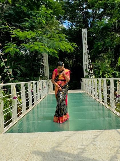 A beautiful shot of Pavithra on a glass bridge, the modern architecture contrasting with her traditional saree.