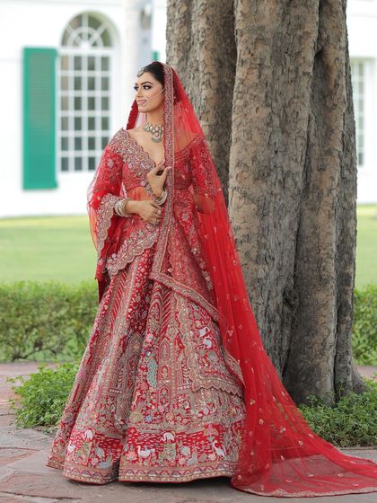 A side profile showcasing the complete bridal look. The long veil and intricate lehenga are paired with makeup that is both elegant and striking.