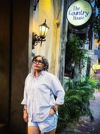 A full-length view of my casual cafe outfit. The oversized shirt worn over denim shorts is a classic summer combination that is both comfortable and effortlessly cool.