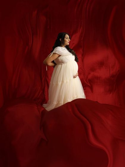 A dramatic and artistic portrait with our cream-colored gown set against a rich red satin backdrop.