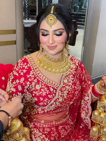 A close-up of the bride getting her golden kalire tied. Her makeup is flawless, with a focus on bold eyes and glowing skin.