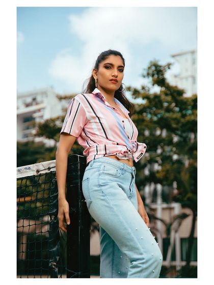 An outdoor lifestyle shot featuring a casual outfit of a striped shirt and jeans. The natural lighting and setting create an authentic, everyday feel.