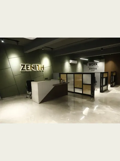 The reception area at the Zenith office, featuring a custom-designed desk and illuminated brand signage against a textured green wall. This entrance sets a professional and modern tone for the entire workspace.