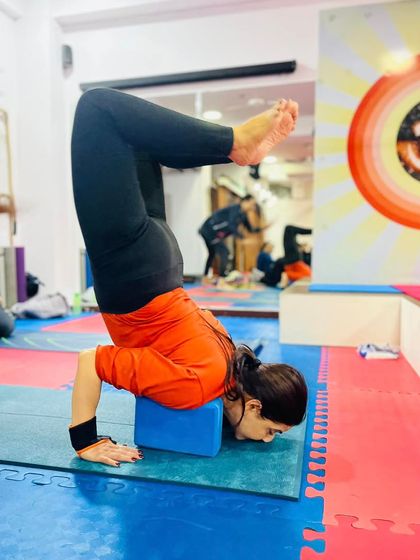 This image shows a student building the strength and flexibility in her forearms and back needed for advanced inversions, with the support of a block.