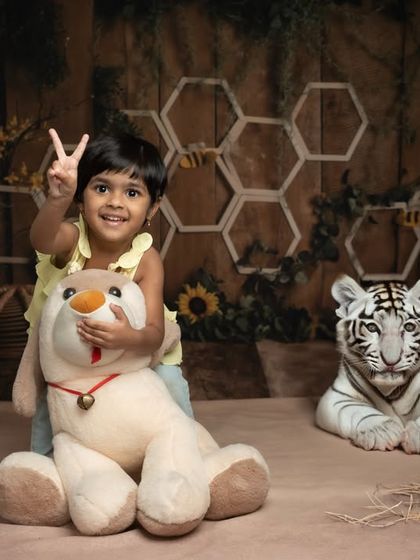 Two years old and full of life! This fun shot from a jungle-themed studio session captures a toddler's excitement as she poses with her stuffed animal friends.