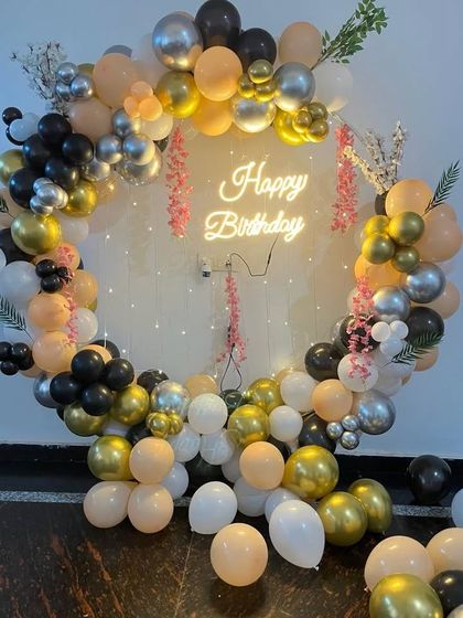 A sophisticated balloon ring in peach, black, white, and gold, with a neon sign.