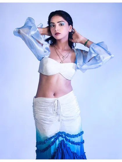 An action pose that brings life to the image, showing how the ruffled sleeves move. This adds a dynamic element to the lookbook, suggesting how the outfit would look and feel in motion.