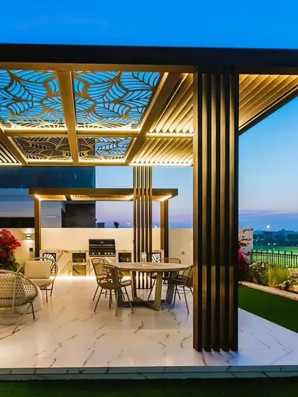 An exquisite outdoor dining area under a pergola with a CNC-cut leaf pattern roof. The integrated lighting and vertical slat walls create a luxurious and intimate atmosphere, perfect for evening gatherings on a terrace.