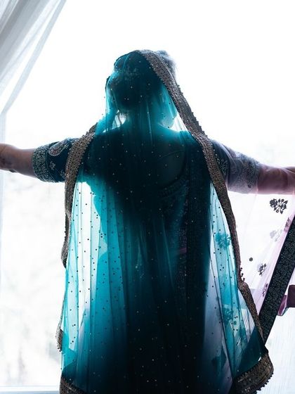 A silhouette of the bride against a bright window, creating a dramatic and artistic portrait that focuses on her form and veil.