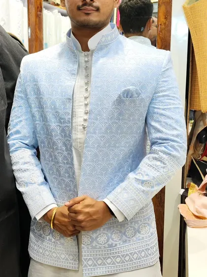 A client wearing a sky blue open Jodhpuri with delicate white embroidery. This is a fresh and elegant option for daytime events.