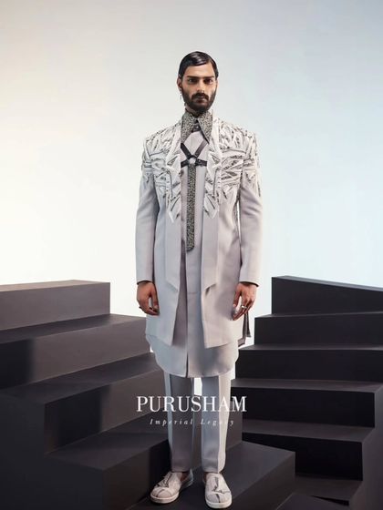 A full-length view of the grey fusion outfit. The asymmetrical cut and unique textures are designed to create a fresh, powerful silhouette that stands apart from traditional menswear.