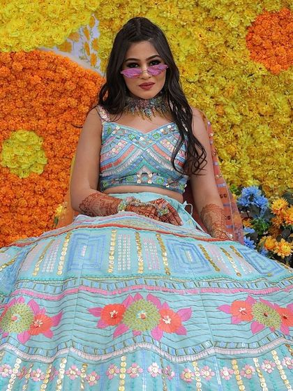 A full-length view of our client's vibrant Haldi lehenga. The custom choker and earrings were designed with a rainbow of colors to match her outfit perfectly.