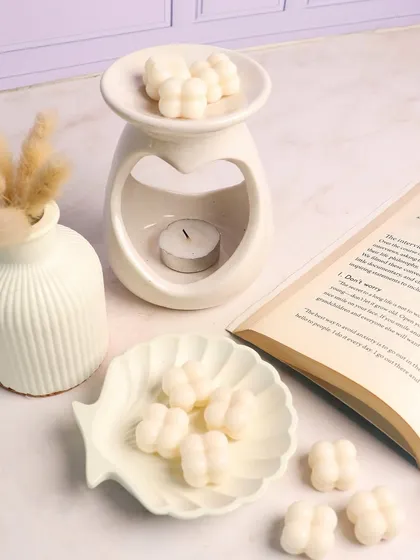 A perfect reading nook setup featuring our heart diffuser, shell-shaped trinket dish, and mini bubble wax melts. Unwind and indulge in enchanting scents.