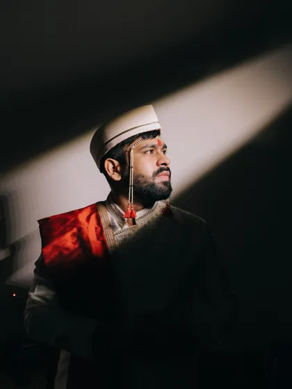 A striking portrait of a Maharashtrian groom in his traditional wedding attire. The focused lighting creates a classic, timeless image that highlights his readiness for the ceremony.