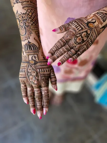 A close-up of a peacock and lotus motif, common in traditional Indian mehendi. The names of family members are written on the fingers in Marathi.