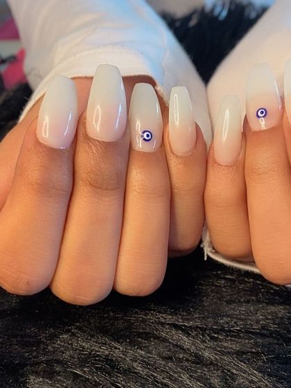 A milky white base with a simple evil eye charm for a touch of protection and style.