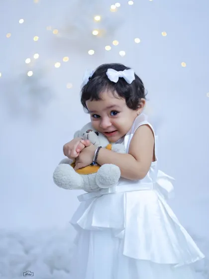 A little angel hugging her teddy bear in our dreamy cloud setup. The soft white textures and twinkling lights create a magical and ethereal atmosphere.