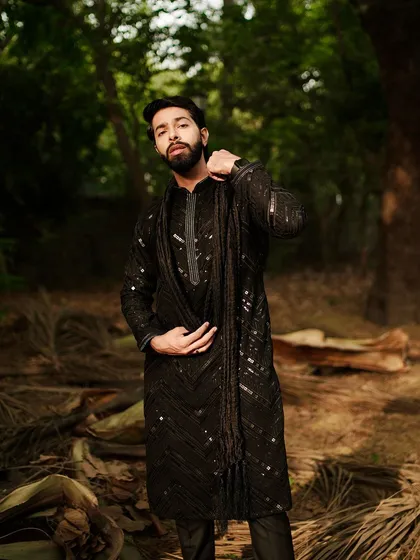 Serving looks hotter than a Delhi summer. This all-black sequined kurta with a matching stole is a statement piece for the man who isn't afraid to shine.