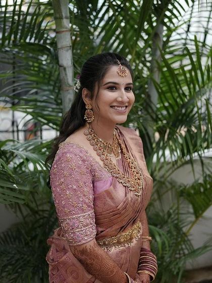 A candid shot of the bride in her dusty rose ensemble, her happy smile is the best accessory.