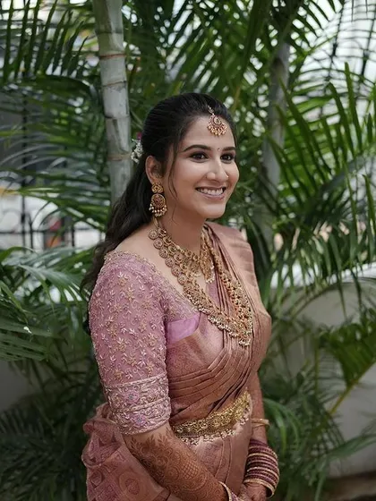 A candid shot of the bride in her dusty rose ensemble, her happy smile is the best accessory.