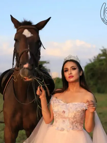 A model in a princess gown shares a moment with a horse, who seems to be nibbling on some hay. These unscripted interactions add character to any photoshoot.