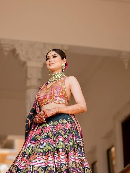 A regal portrait of Kashish at her Mehendi ceremony in Udaipur. The intricate, multi-colored lehenga is paired with a clean makeup look, a classic bun, and a statement choker.
