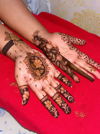 A unique bridal design with two different patterns on each hand. One hand features a central floral medallion, while the other has a trailing pomegranate vine, showing how we can customize the art to your preference.