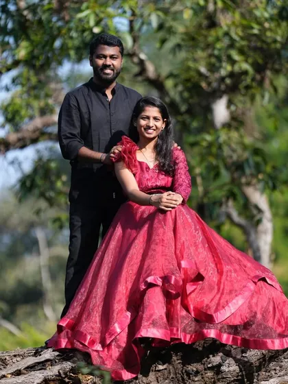 A beautiful couple's portrait in the woods. The red organza gown with its ruffled shoulder detail is a fashionable and unique choice.