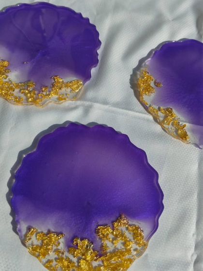 This set of three geode-style resin coasters features a rich purple color that fades into a clear base, elegantly accented with a sprinkle of gold flakes.
