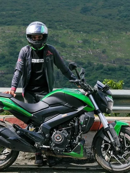 Standing with the machine that takes us places. A rider and his Dominar against the green landscape of the Karnataka hills.