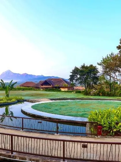 The beautifully landscaped gardens of a Sakleshpur resort, with a central lawn and water features, all set against a backdrop of the Western Ghats.