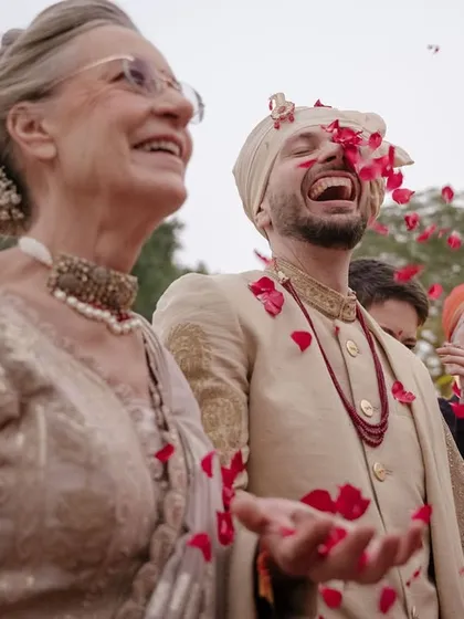Ted shares a laugh with his mother, showered in red petals from Karna's family. This is a beautiful moment of two families coming together, filled with genuine happiness and warmth.