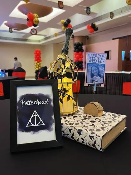 The magic is in the details. For a Harry Potter themed party, I created custom table centerpieces featuring a 'Potterhead' sign, a 'Have You Seen This Wizard?' photo holder, and a candle-lit lantern on a themed book.