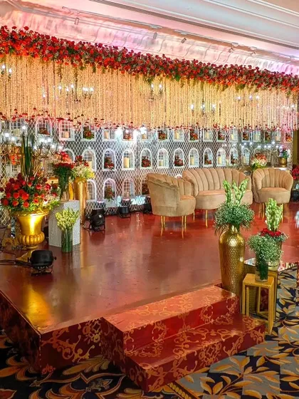 This reception stage is a floral fantasy. A dense canopy of red and white flowers hangs over the seating area, while the intricate white backdrop adds a layer of texture and elegance.