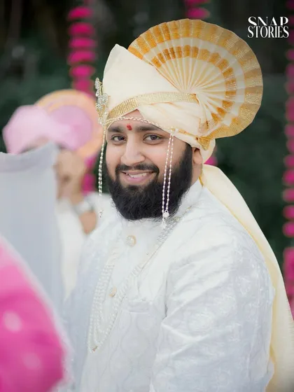 A handsome groom in his traditional white sherwani and pheta. Our groom portrait photography aims to capture his personality and anticipation on the wedding day.