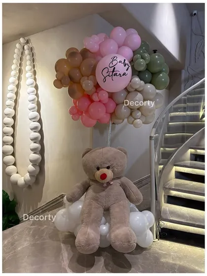 A large teddy bear decoration adds a cuddly and welcoming touch to the party decor.