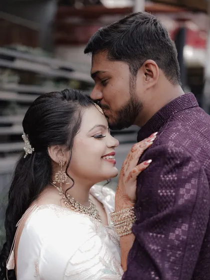 A close-up, romantic shot of the groom-to-be kissing his fiancée's forehead during their engagement photoshoot.