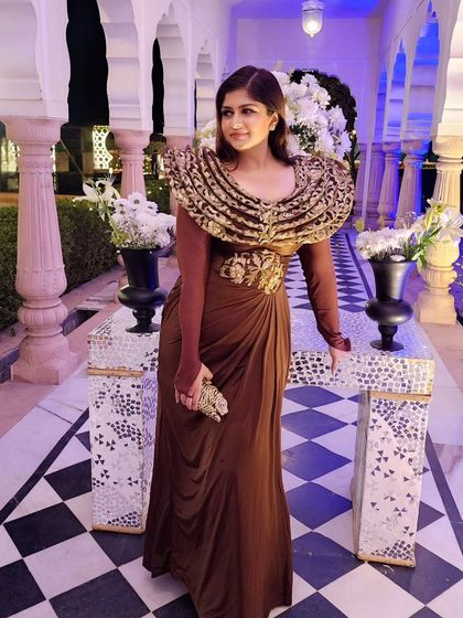 A stunning brown gown with a dramatic, embroidered collar. This is a perfect example of a statement piece for a wedding function that is both timeless and trendy.