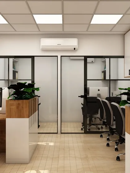 A view showing the flow of the open-plan office, with glass-walled cabins in the background. This design maintains a sense of openness while providing private areas for meetings or focused work.