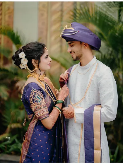 A classic portrait of a Maharashtrian couple. The bride adjusting the groom's 'pheta' is a gesture of love and care.