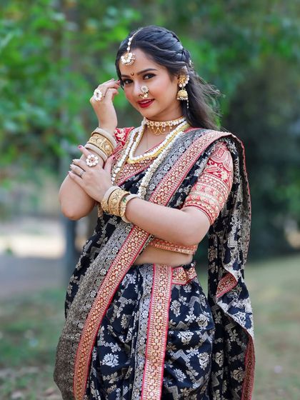 A close-up portrait highlighting the bridal makeup and the beautiful combination of the black saree and gold jewellery.